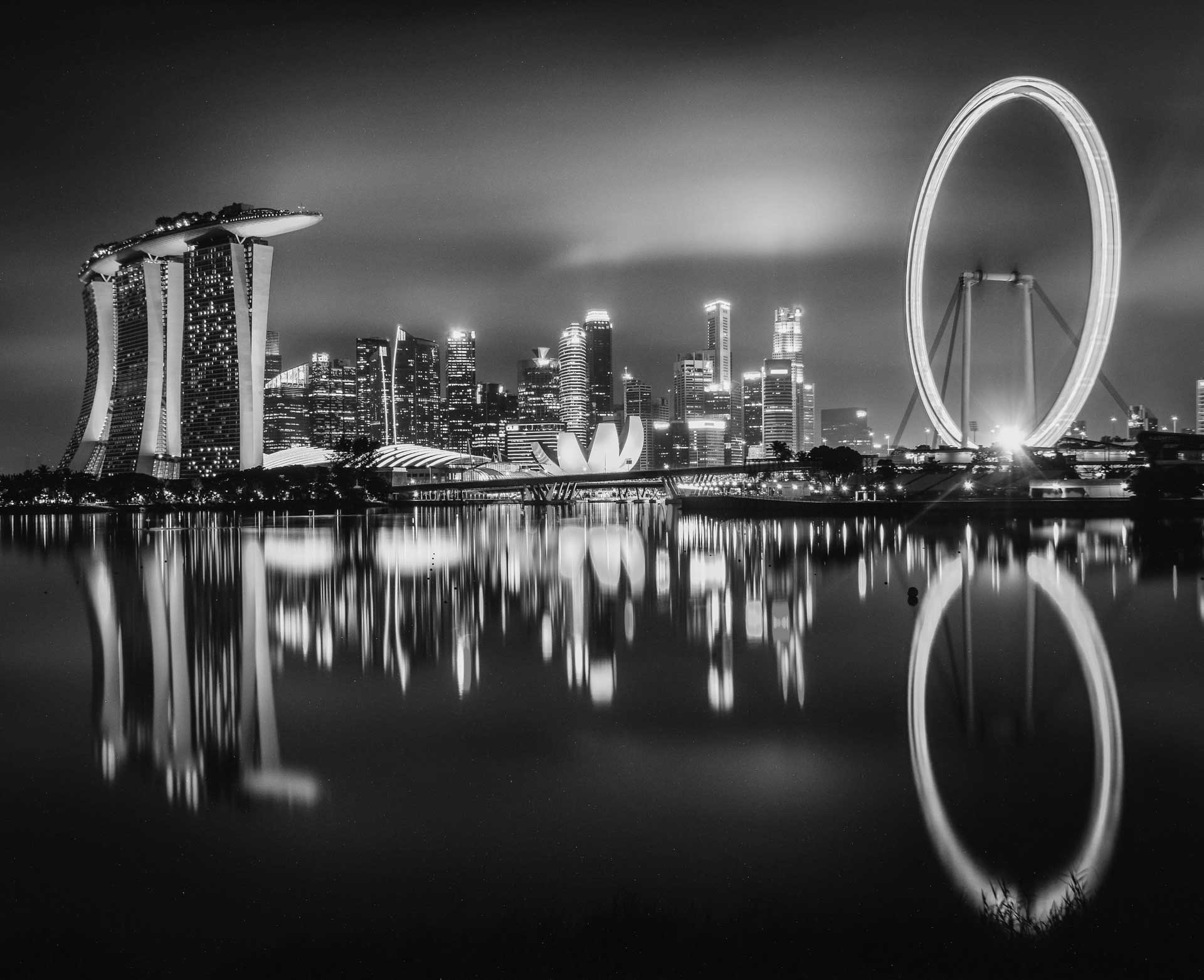 Black-and-white photo of Singapore with Marina Bay Sands on the left and the Singapore Flyer giant ferris wheel to the right